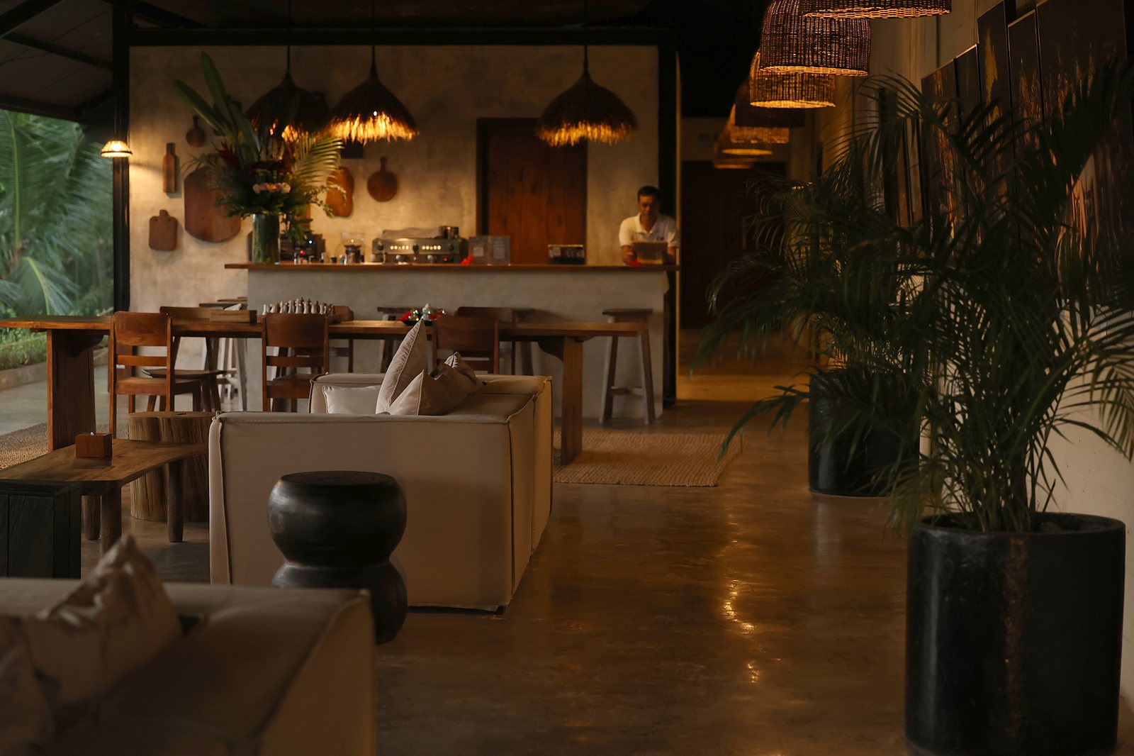 The bar in the evening: rattan lamps over the counter, the bartender at work