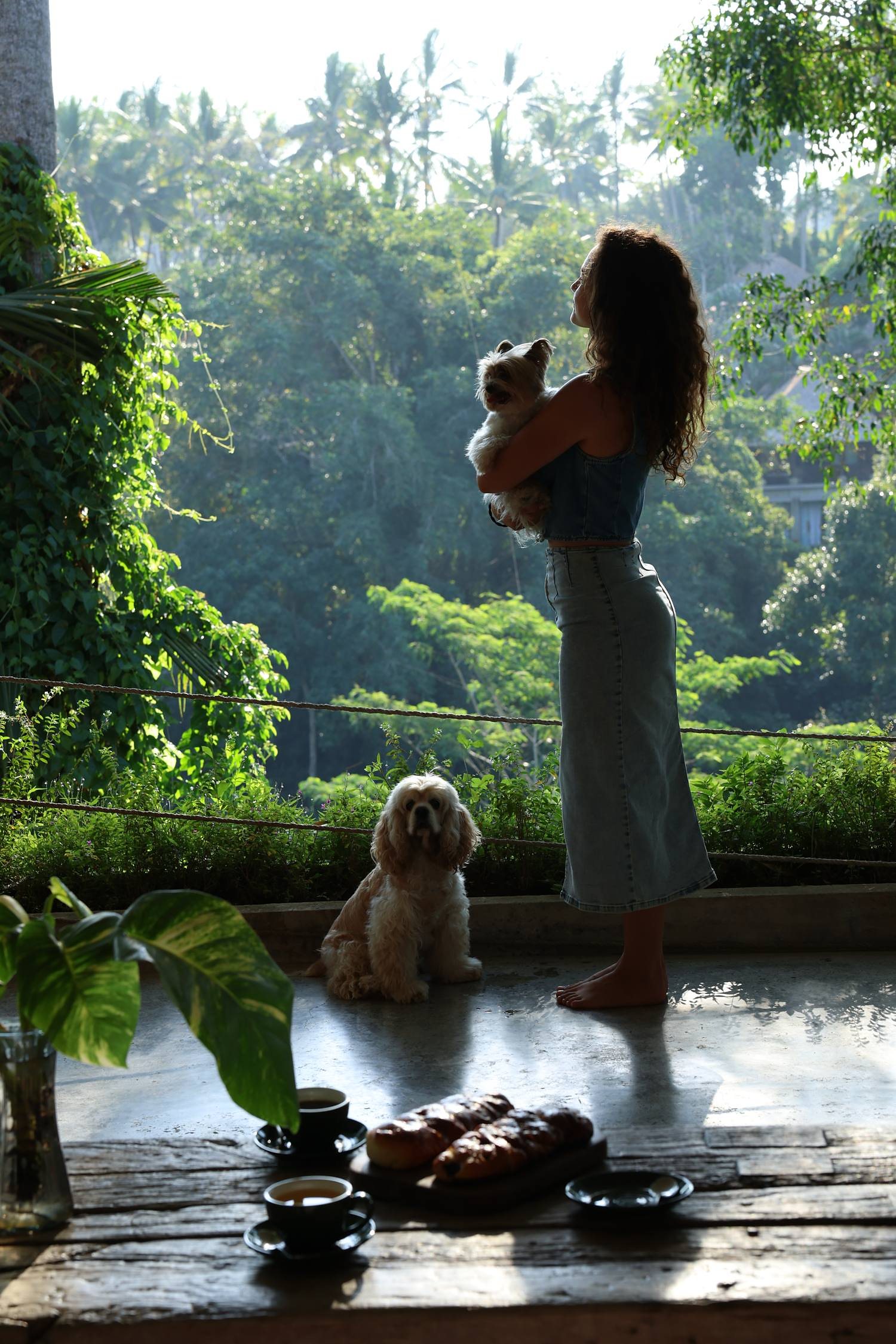 A guest on her terrace above the jungle with two dogs, coffee and pastries on the low table