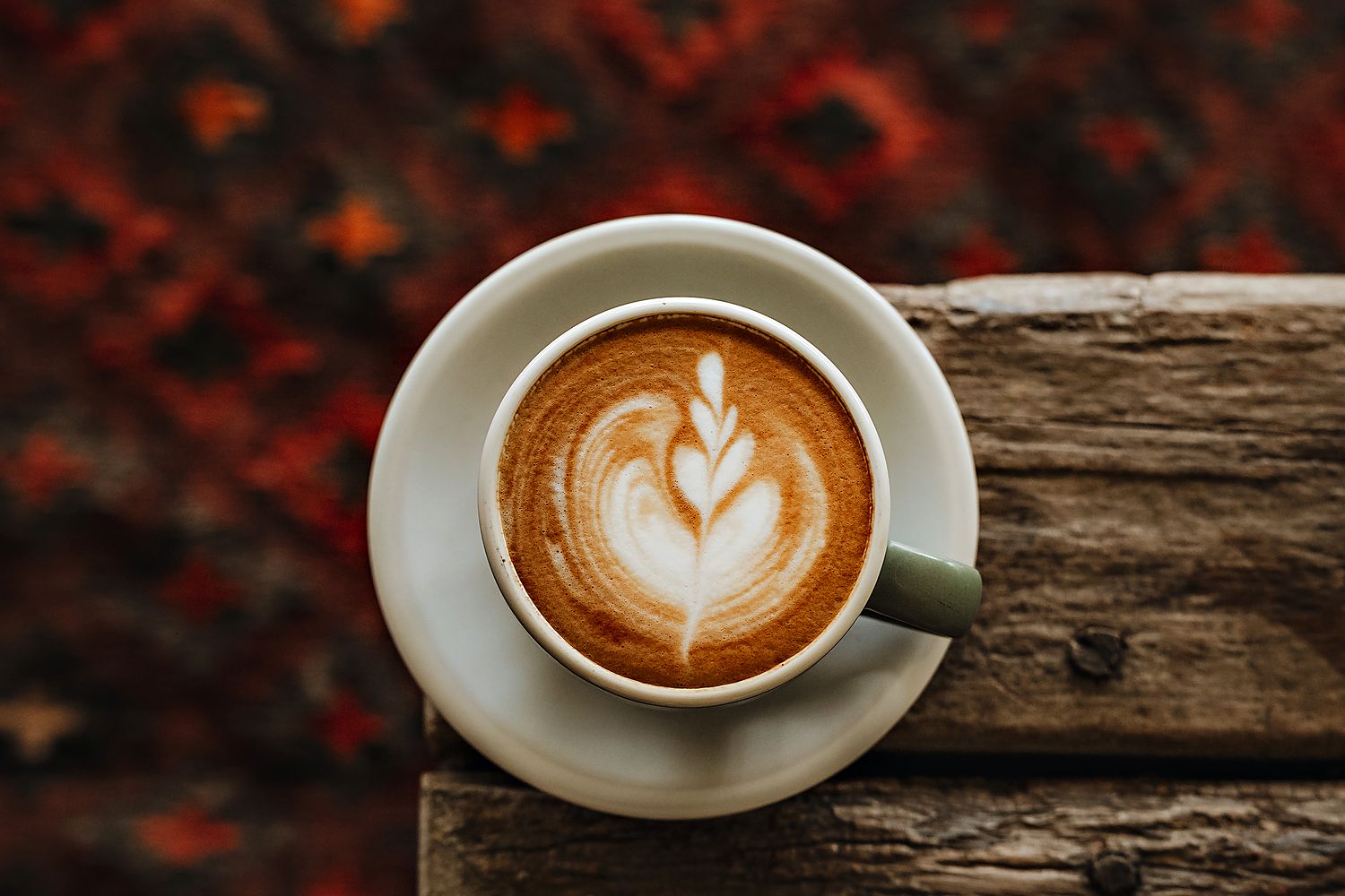A latte on the edge of the wooden table in the Gem 2-Bedroom Villa, the kilim rug below