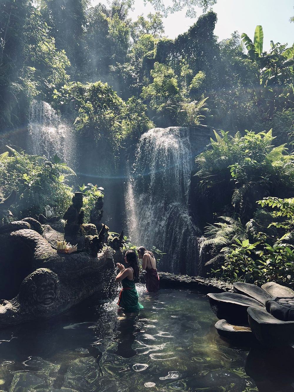 Guests standing under the waterfall at Taman Beji Griya
