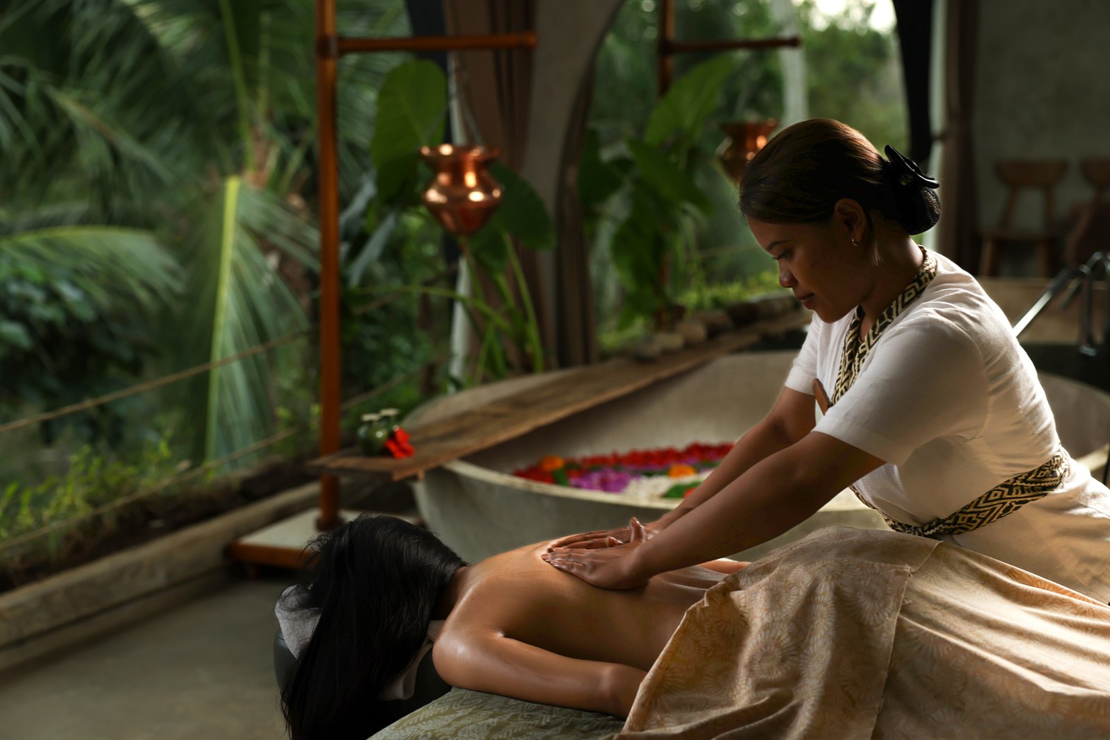 A Balinese massage in an open spa room, the flower bath and the palms behind