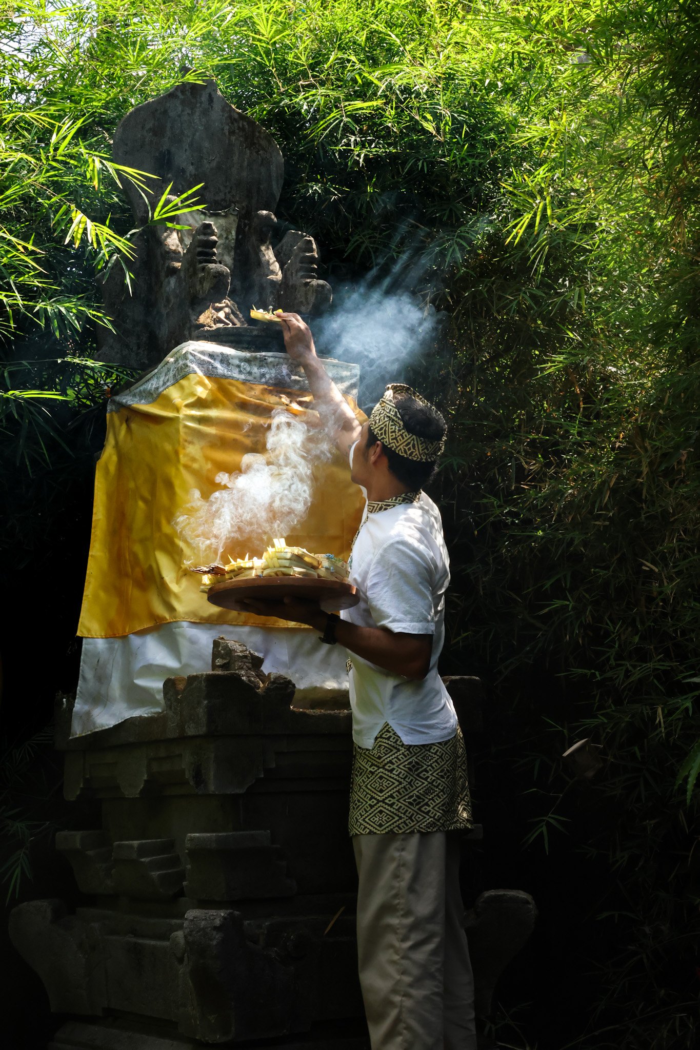 A morning offering at the shrine, incense smoke rising through the bamboo