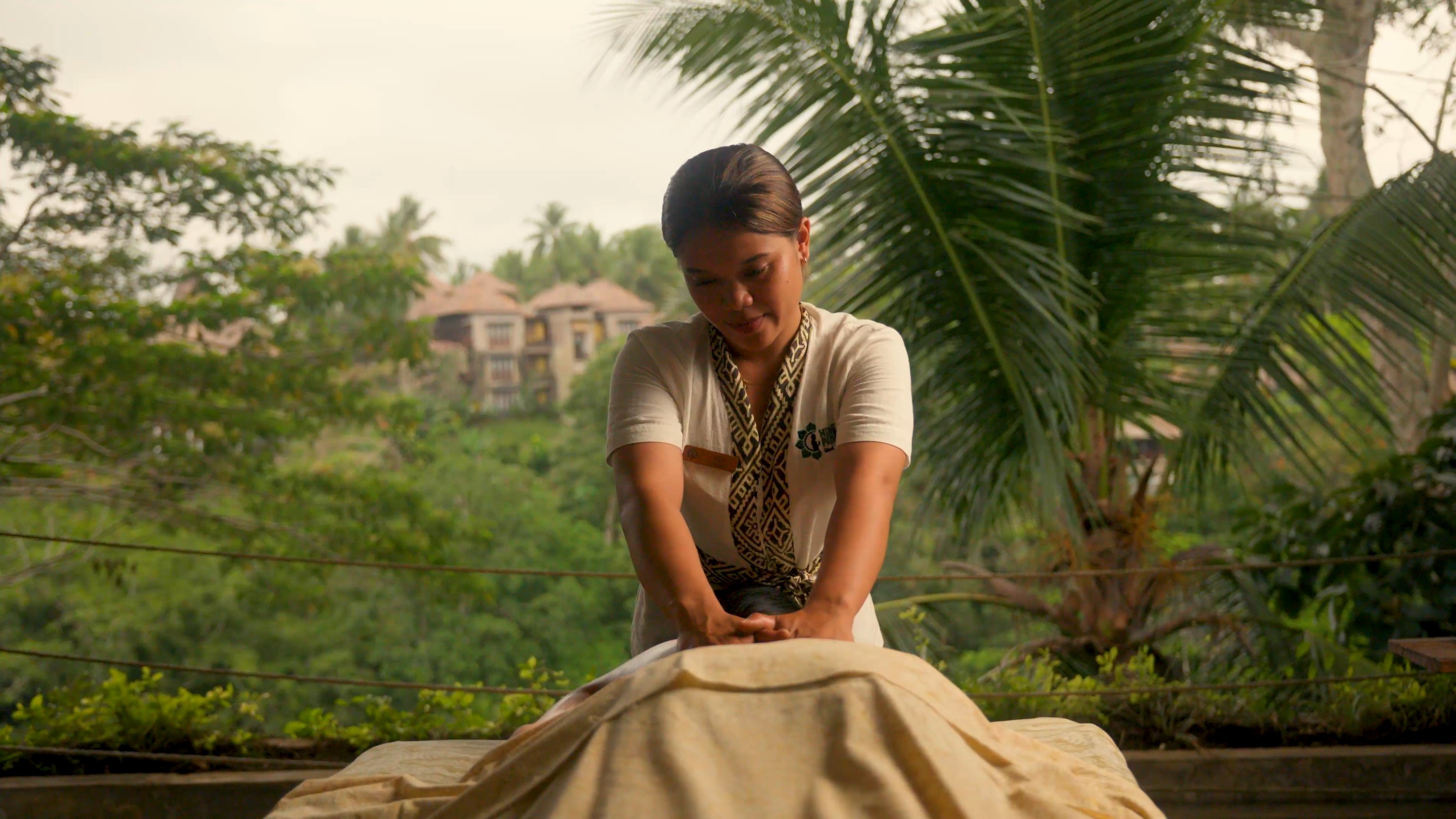A Balinese massage in the open spa room, the valley and the palms behind the therapist