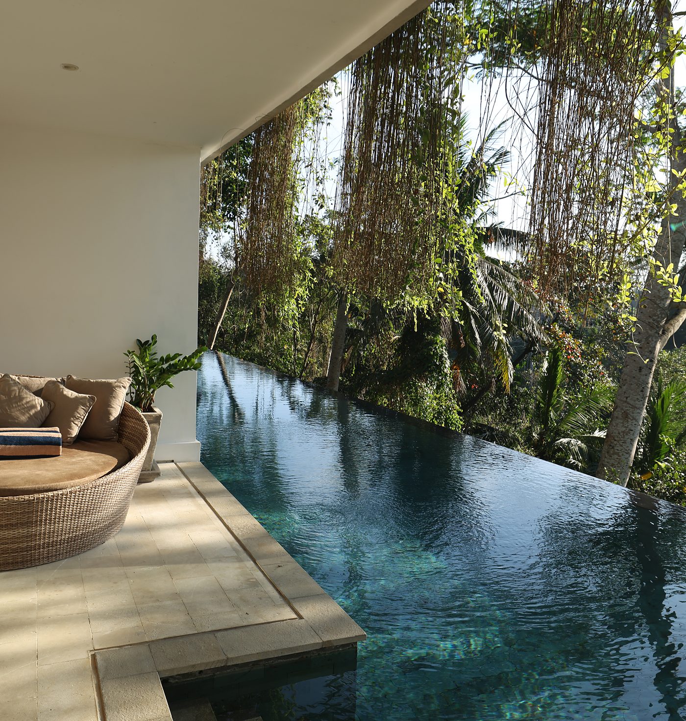 A Premiere Suite terrace: a daybed by the infinity pool, the jungle beyond