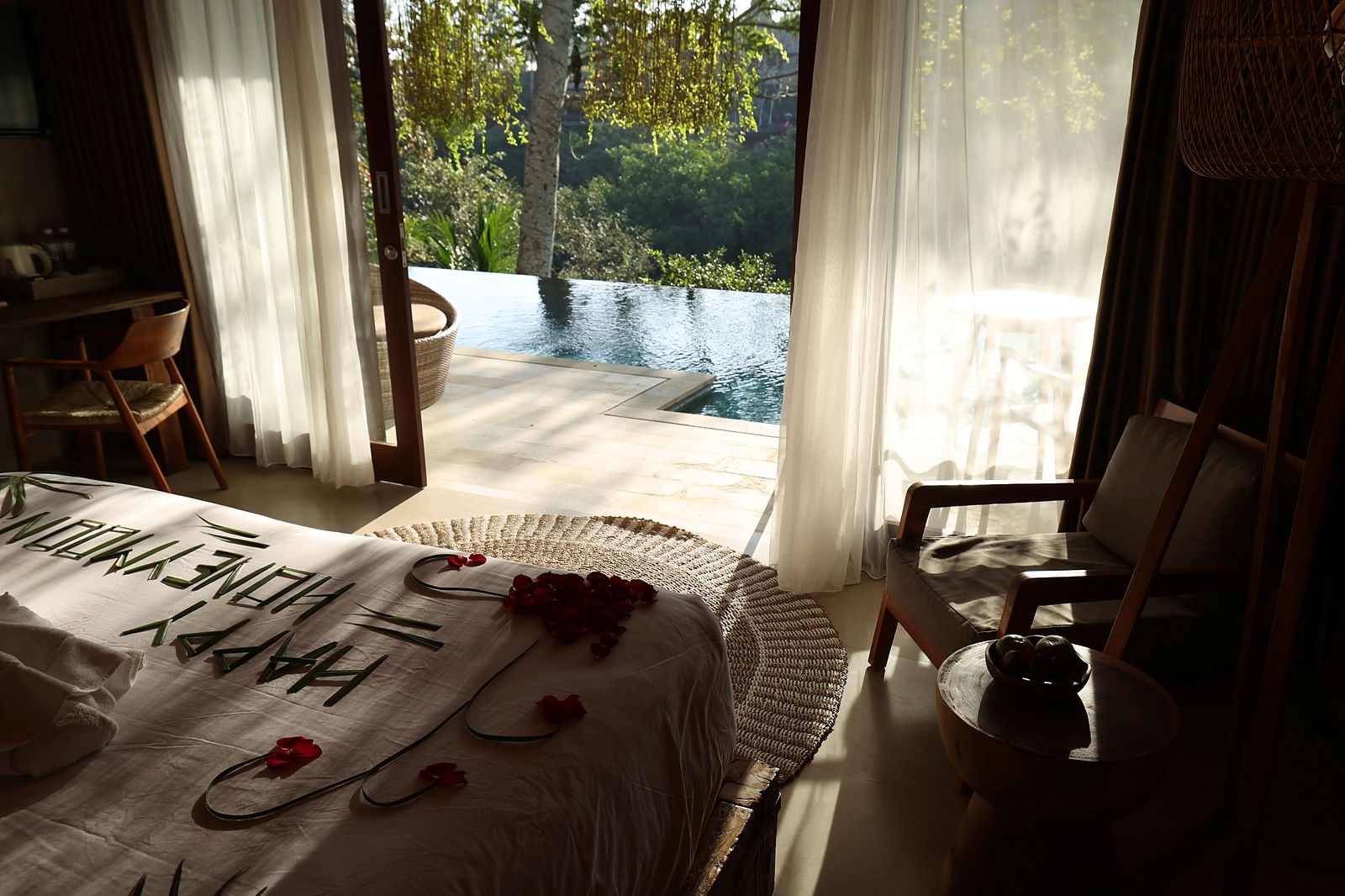 A Premiere Suite bed set for two, the private pool beyond the open doors